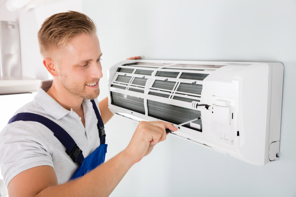 HVAC technician cleaning and repairing a ductless mini split AC in Kingman, AZ