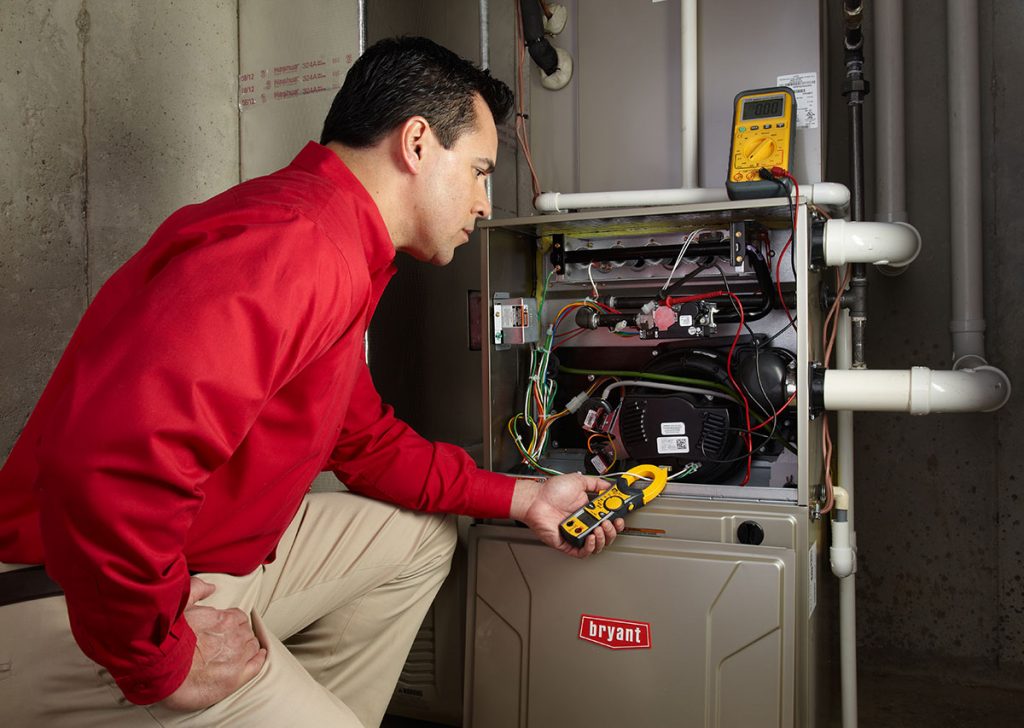 Heating and air conditioning technician servicing an indoor furnace in Kingman, AZ