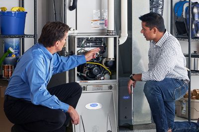 65df8c11f3e4c468cbd351a5_furnace repair vs replacement – Copy HVAC technician explaining furnace repair and maintenance to a homeowner in Kingman, AZ